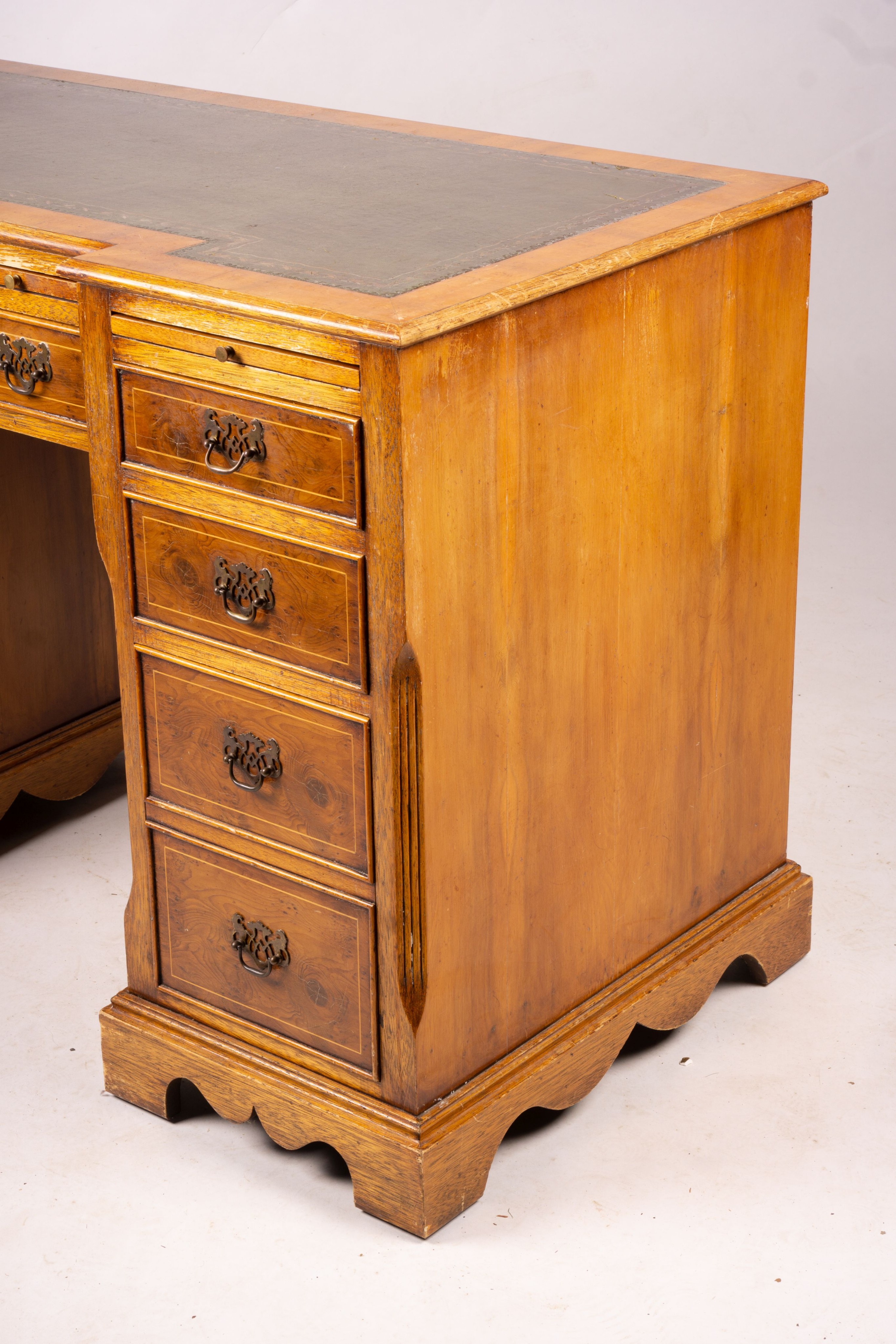 A reproduction yew inverse breakfront kneehole pedestal desk fitted green skiver, width 114cm, depth 58cm, height 77cm